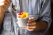 Chia Pudding On Coconut Milk With Raspberries And Peach In A Glass Jar In Female Hands With A Spoon. Raw Vegan Healthy Food Concept