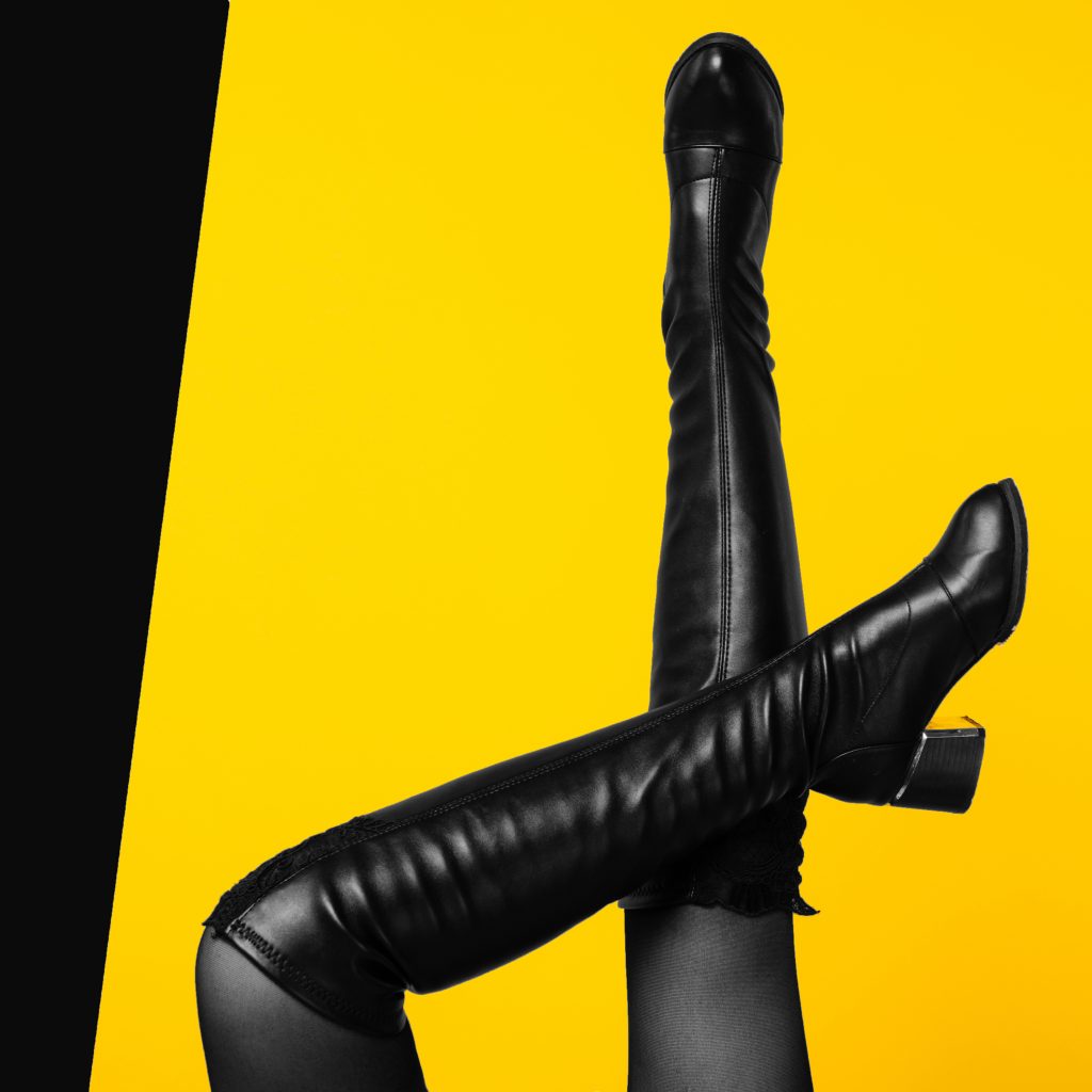 Sexy Legs Wearing Black Leather Boots On Yellow Background