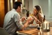 Happy Couple Toasting With Champagne During Dinner At Dining Table.