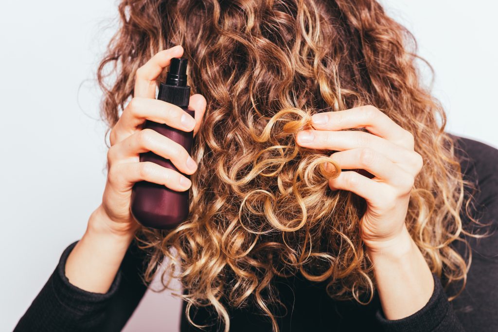 Close Up Young Woman Spraying Cosmetic Oil