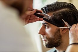 Young Man Having A Haircut At Barber Shop.