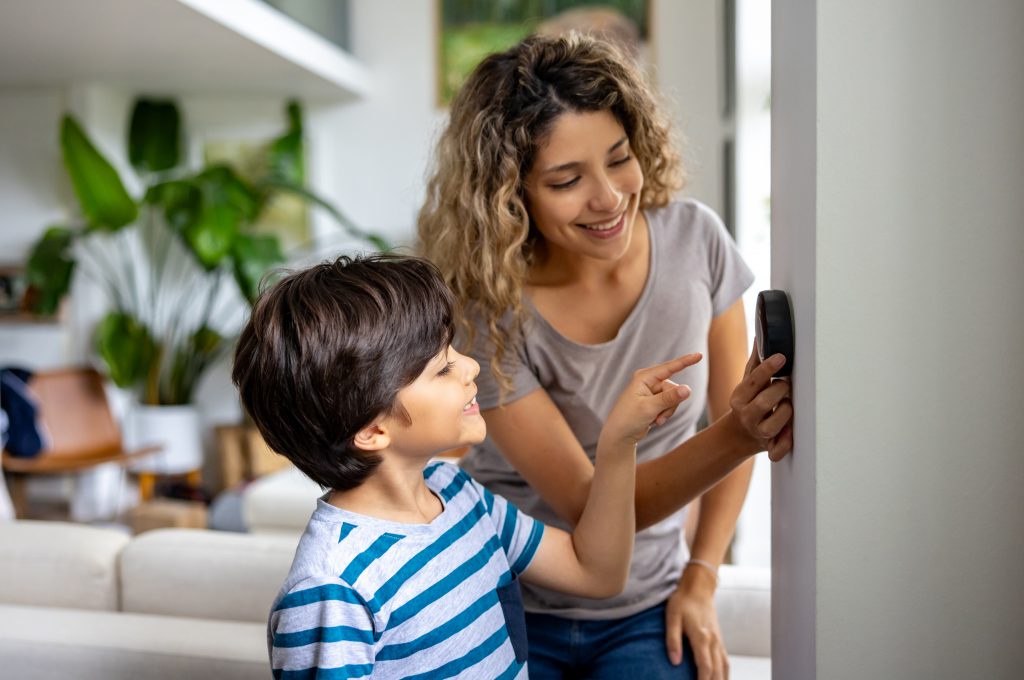 Mother And Son At Home Using A Smart Thermostat