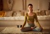 A Portrait Of A Woman Doing Meditation At Home, Keeping Her Eyes Closed, Has Candles On The Side.