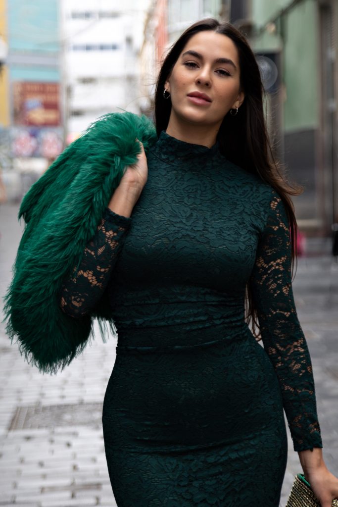 Fashion Model Wearing Emerald Green Lace Dress And Faux Fur Stole Walks Down City Street