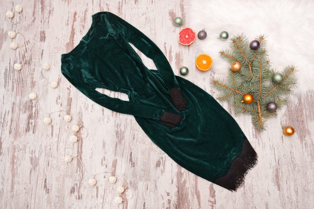 Emerald Velvet Dress With Sleeves And Spruce Branch On A Wooden Background. Fashionable Concept