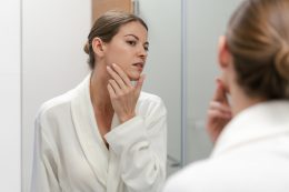 Woman In Bathrobe Looking In Mirror At Bathroom