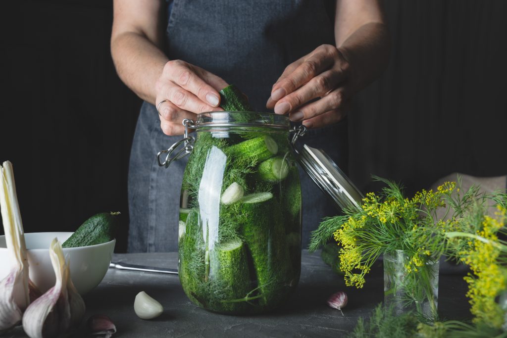 Woman Cooking Marinated Cucumbers With Garlic And Dill On Black. Rustic Dark Style.