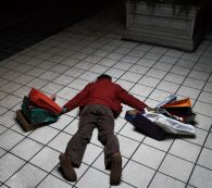 Man Holding Shopping Bags Lying Face Down On Floor, Rear View