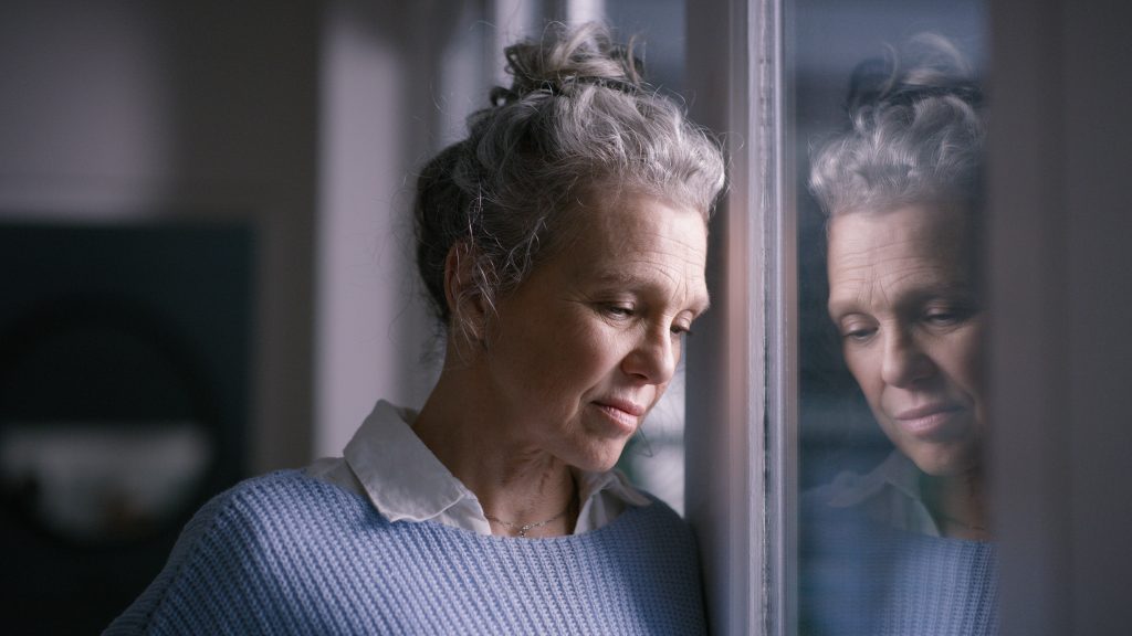 Depression, Sad And Senior Woman By Window Looking, Upset, Lonely And Unhappy In Retirement Home. Mental Health, Loneliness And And Depressed Elderly Female Thinking Of Problem, Issues And Crisis