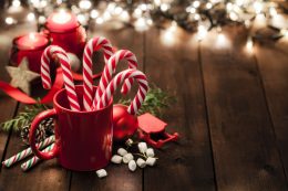 Christmas Backgrounds: Candy Canes In A Red Mug On Rustic Wooden Table. Copy Space