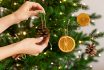 Female Hands Hanging Handmade Decoration On Christmas Tree.