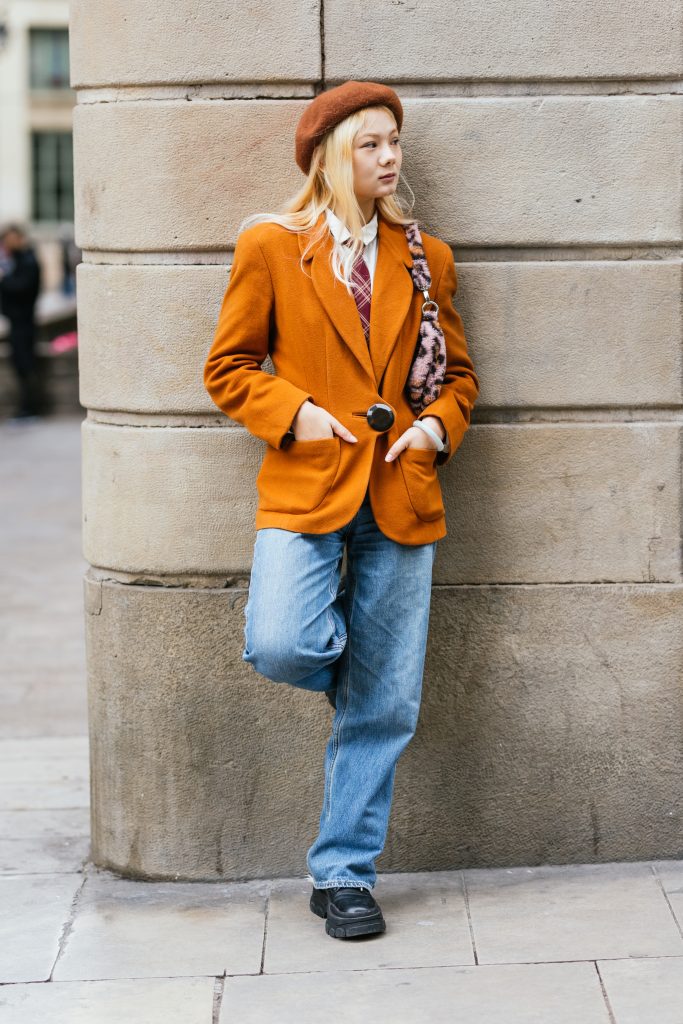 Stylish Asian Woman Leaning On Wall With Hands In Pocket On The Street.