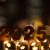 2025 Festive Candles Stand Near Golden Stars Of Lights Against A City Bokeh Background At Night. New Year 2025 And Christmas Card