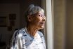 Senior Woman Looking Out The Windows Of Her Home