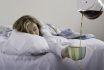 A Woman In Bed Holding An Overflowing Coffee Mug In Her Hand