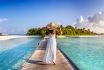 Back View Of A Woman In White Dress Walking Down A Pier Towards A Tropical Island