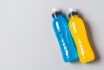 Isotonic Energy Drink Copy Space Grey Background. Bottles With Blue And Yellow Flavored Mineral Vitamin Sport Beverage Top View.