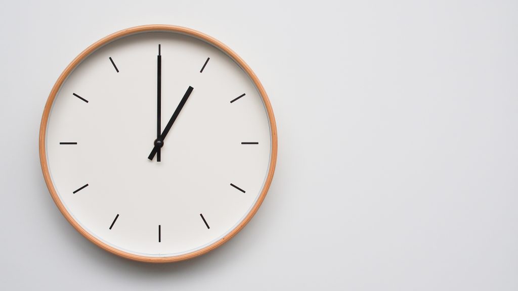 Minimalist Wooden Wall Clock On White Wooden Surface With Space For Text Time Set At 13.00/01.00