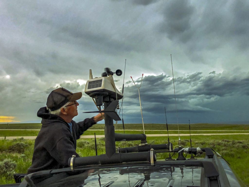 Storm Chaser Adjusts The Rooftop Weather Station On His Chase Vehicle As A Severe Storm Builds In The Background