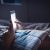 Woman Using Phone Late At Night In Bed. Person Looking At Text Messages With Cell In Dark Home. Hipster Online Dating Or Texting With Smartphone. Sexting Or Cheating Concept.