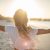 Cheerful Young Woman Embracing Nature At Sunset; Female Standing On Beach Arms Outstretched