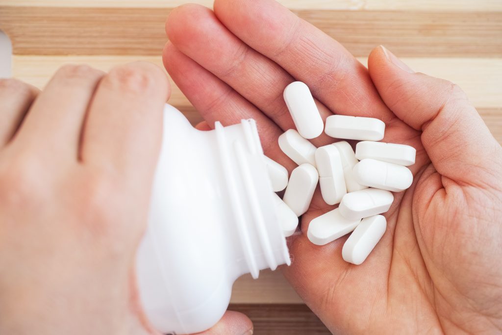 Woman Taking Magnesium Pills Out Of A Bottle