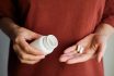 A Woman Pours Pills Or Vitamins From A Jar Onto Her Hand. Taking Vitamins Or Medications. The Concept Of Health Care, Medicine, Pharmacies, Disease Prevention. A Jar With Pills Or Vitamins In The Hand