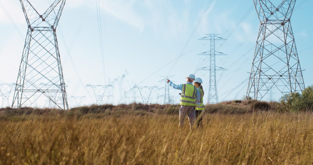 Teamwork, Electrical Engineer And Inspection In Power Station With People For Electricity Transmission And Tower Check. Engineering, Back And Collaboration For Energy Distribution Or Mockup In Field