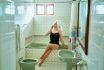 Elegant Woman Relaxes In Vintage Bathroom, Applies Face Cream, Enjoys Self Care Ritual. Retro Bath, Skincare Routine, Pampering At Home. Female In Bodysuit With Towel On Head, Grooming In Calm Setting