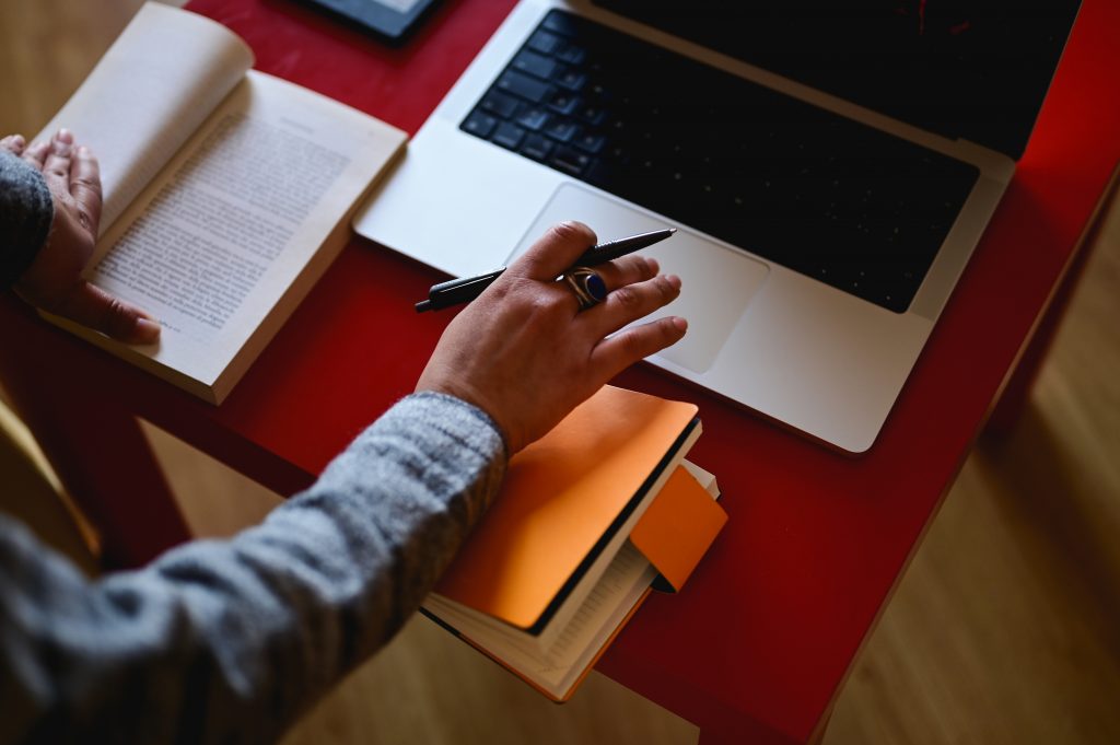 Woman's Hand Working With Laptop And Book.