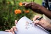 Close Up Of A Woman Drawing Flowers In Her Notepad