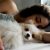 Close Up Of A Dog Lying On The Bed With Its Owner At Home