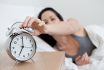 Young Woman Reaching For Alarm Clock