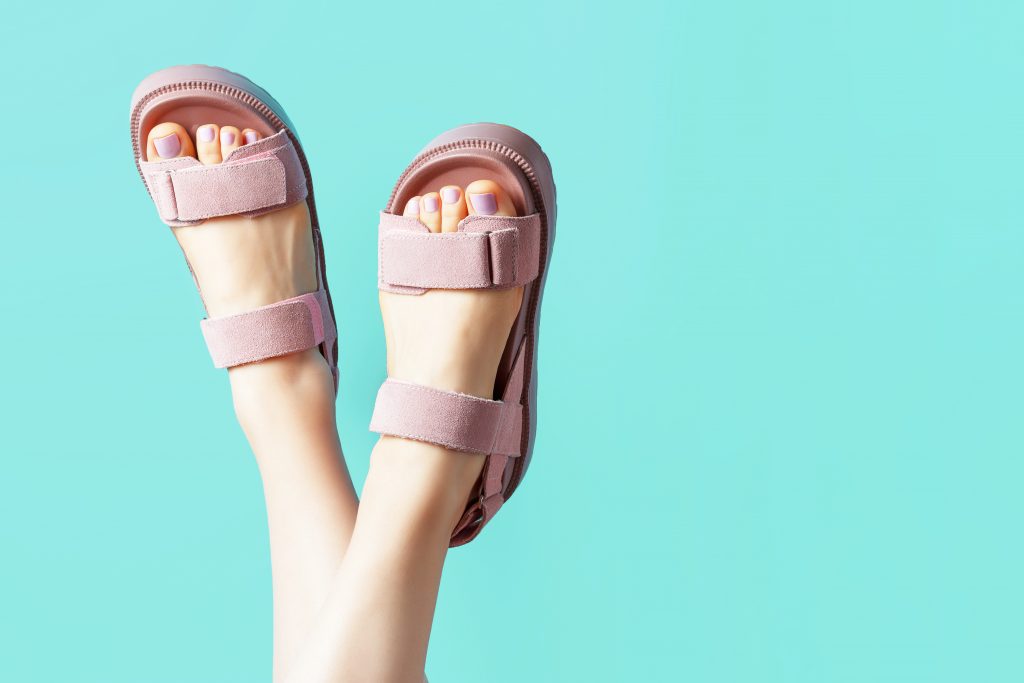Hello divatimádók! Ezekre a cipőtrendekre érdemes figyelni 2025 nyarán 3 Female Legs In Pink Sandals Upside Down On Blue Background.