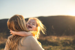 Happy Girl Kid Hugging Mom In The Nature