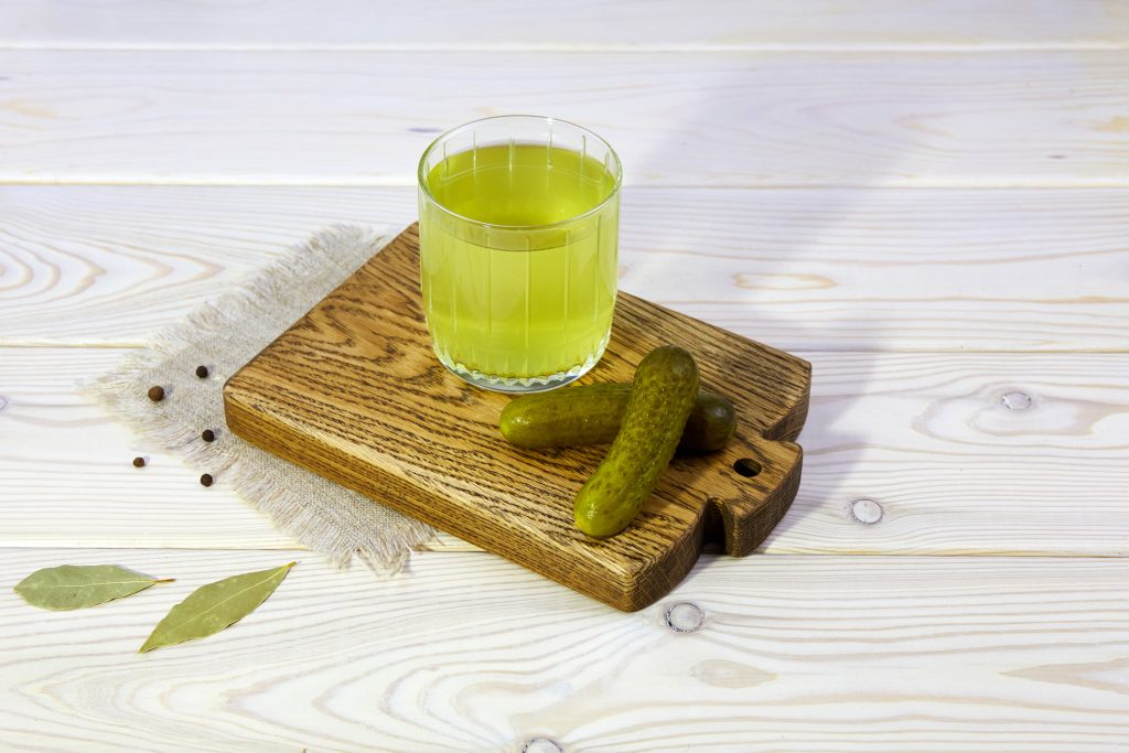 Pickle Juice Or Cucumber Pickle On A Wooden Background. Healthy Energy Drink For Athletes.